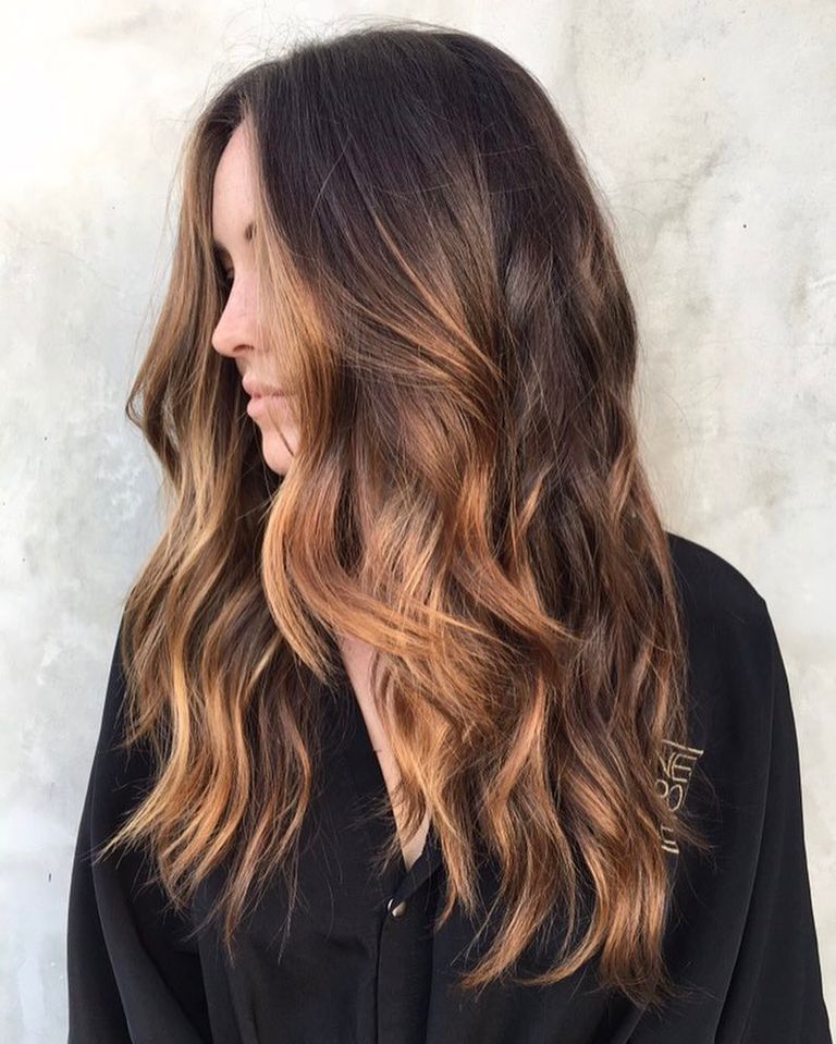 Long dark brown hair with soft caramel balayage, styled in loose waves