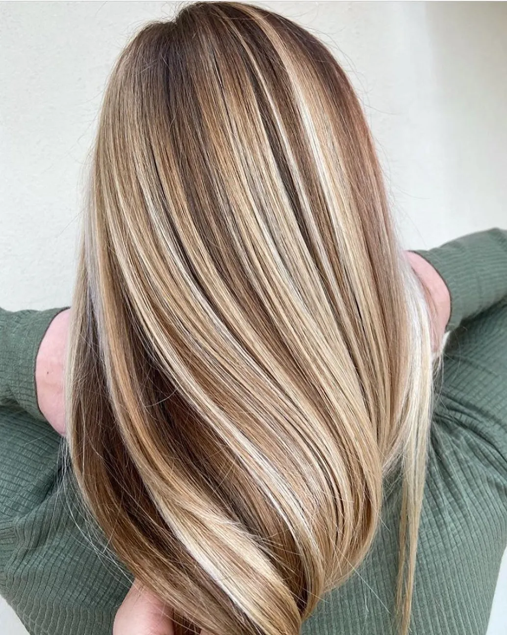 Straight, glossy hair with blended blonde and caramel highlights, seen from behind