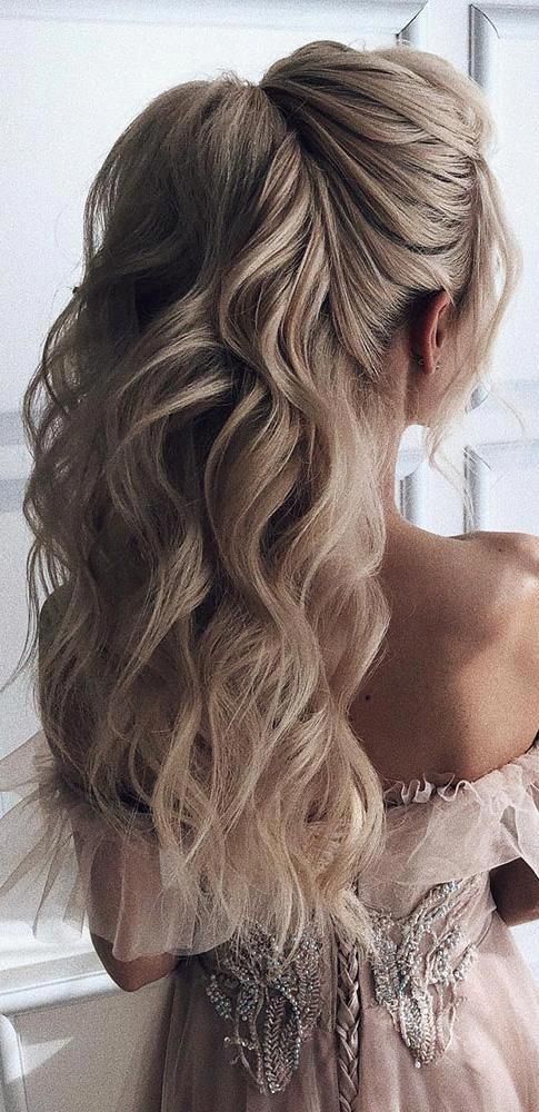 A high, voluminous ponytail with long ash-blonde waves